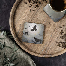 Load image into Gallery viewer, Corkwood underside, glossy finish on top. Available in 1 or 4 pc sets. 9.5 x 9.5cm. Scene of crows, ravens, blackbirds flying