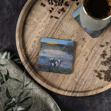 Load image into Gallery viewer, Corkwood underside, glossy finish on top. 1 or 4 pc sets. 9.5 x 9.5cm. Black & white cow eating grass at sunrise. Sunrays