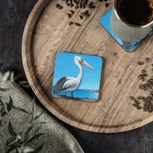 Load image into Gallery viewer, Corkwood underside, glossy finish on top. 1 or 4 pc sets. 9.5 x 9.5cm. Australian pelican overlooking a beach from a cliff