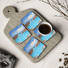 Load image into Gallery viewer, Corkwood underside, glossy finish on top. 1 or 4 pc sets. 9.5x9.5cm. Outback Australia Islands, clouds, sunrays, blue water