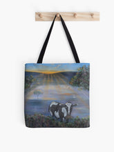 Load image into Gallery viewer, Original painting of a black and white cow eating with the sun rising on a 41 x 41cm tote bag