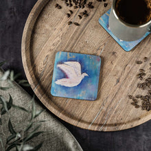 Load image into Gallery viewer, Corkwood underside, glossy finish on top. 1 or 4 pc sets. 9.5 x 9.5cm. White bird / dove flying over an abstract background
