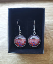Load image into Gallery viewer, original artwork of a sunrise (in the form of the ANZAC Crest) with a silhouette of a soldier kneeling next to his horse drinking from his hat in a field of red and purple poppies on 16mm surgical steel fishhook earrings
