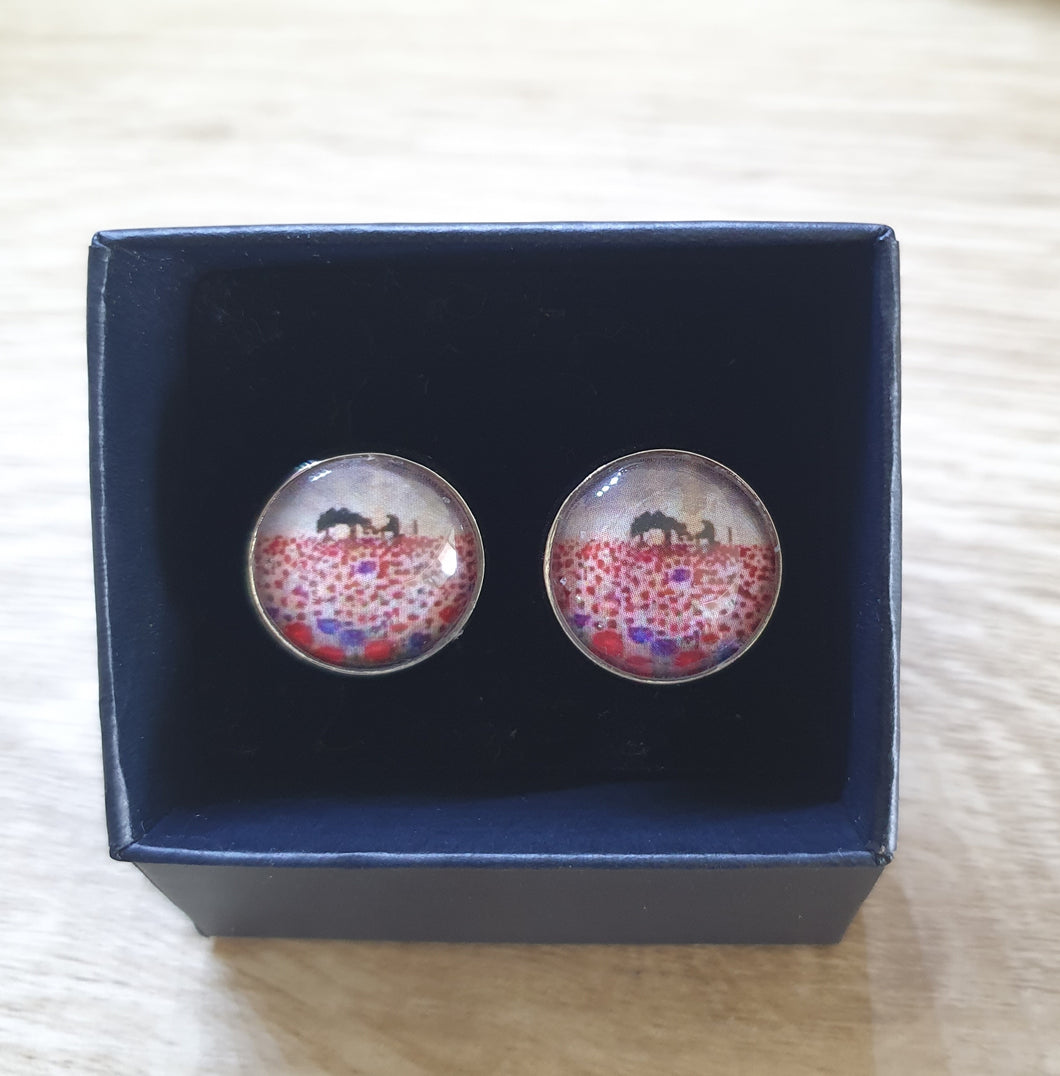 original artwork of a sunrise (in the form of the ANZAC Crest) with a silhouette of a soldier kneeling next to his horse drinking from his hat in a field of red and purple poppies on 16mm surgical steel studs