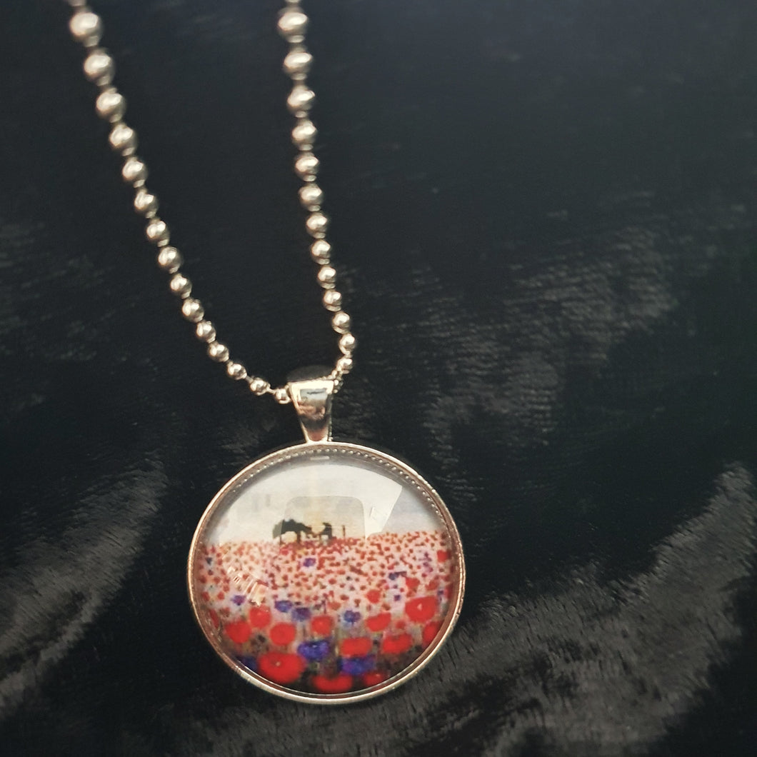 original artwork of a sunrise (in the form of the ANZAC Crest) with a silhouette of a soldier kneeling next to his horse drinking from his hat in a field of red and purple poppies on a 30mm silver coloured round pendant with a 60cm ball chain