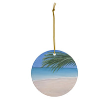 Load image into Gallery viewer, Original painting of a tranquil  tropical beach with  palm leaves on a round ceramic ornament with hanging string
