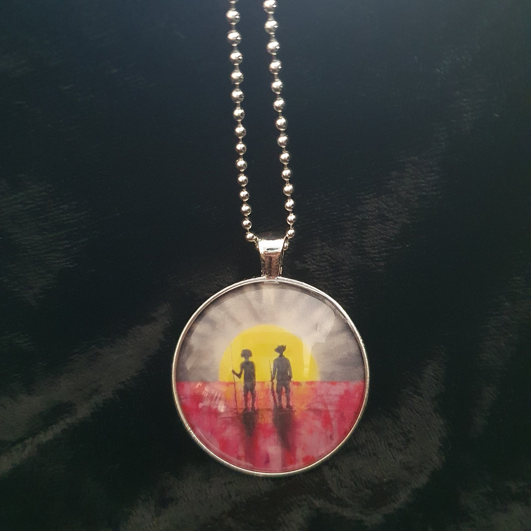 Original painting of a rising sun which is an abstract version of the Aboriginal flag with the silhouette of an Aboriginal holding a spear and a soldier holding a gun surrounded by red poppies on a 38mm silver coloured round pendant with a 60cm ball chain