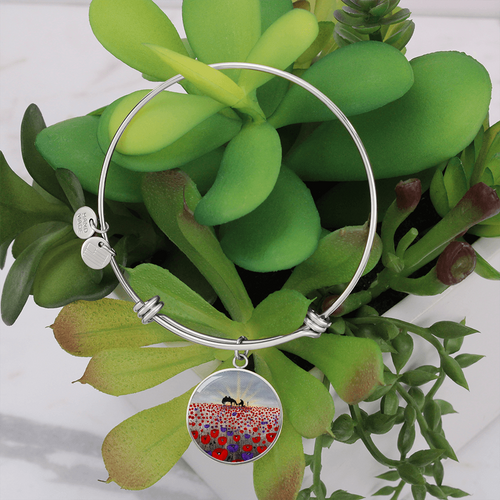 original artwork of a sunrise (in the form of the ANZAC Crest) with a silhouette of a soldier kneeling next to his horse drinking from his hat in a field of red and purple poppies on a surgical steel adjustable bangle with charm 