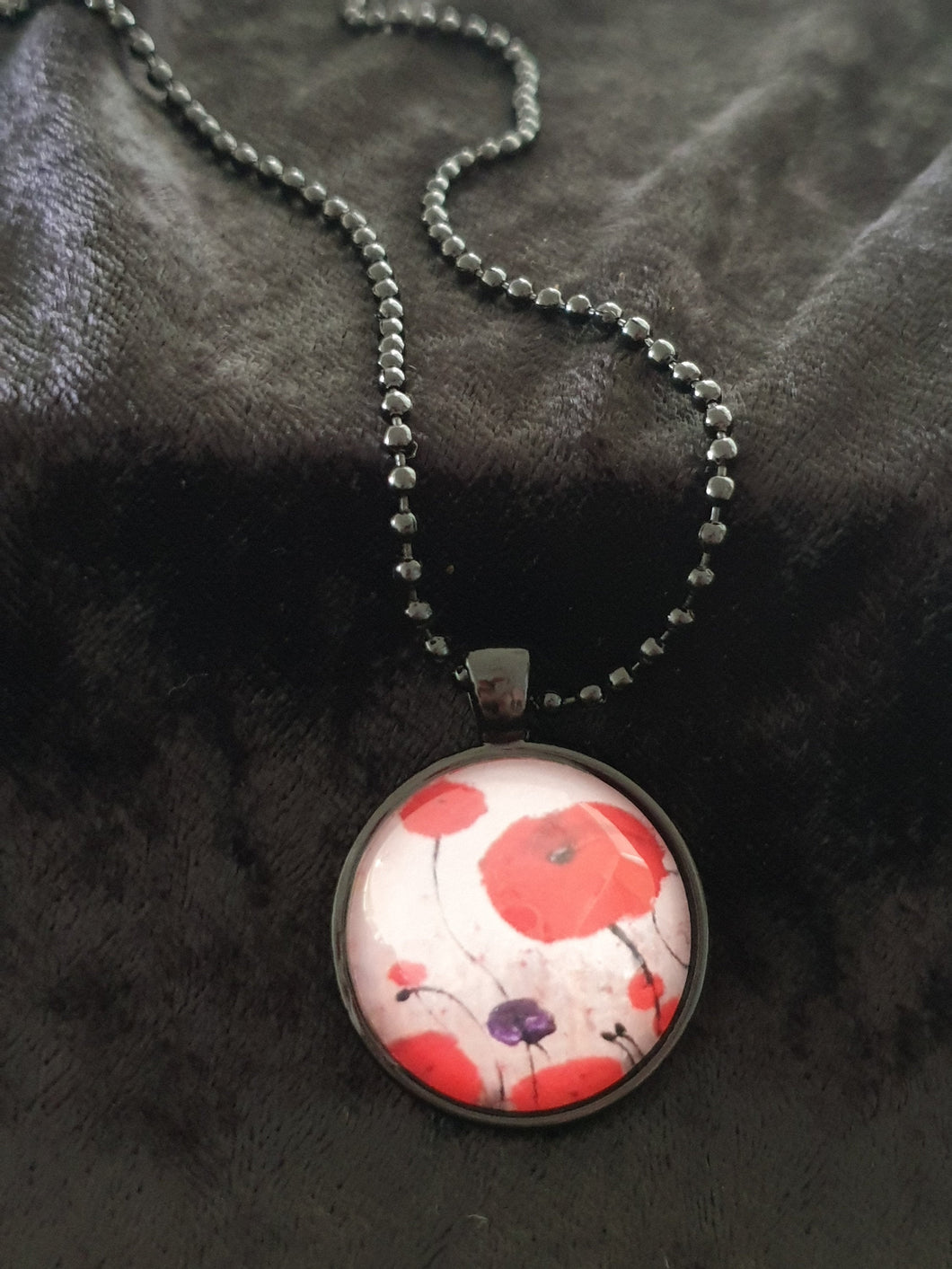 Original painting of red poppies with an abstract background on a black coloured 25mm round pendant with a 60cm ball chain