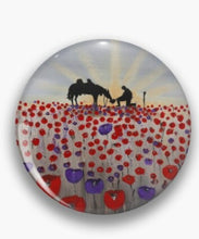 Load image into Gallery viewer, Original artwork of a sunrise (in the form of the ANZAC Crest) with a silhouette of a soldier kneeling next to his horse drinking from his hat in a field of red and purple poppies on a round unisex pin.
