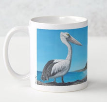 Load image into Gallery viewer, Original painting of an Australian pelican standing rocks overlooking a beach on a ceramic mug
